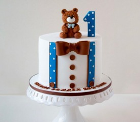  A cake with a teddy bear on top and a number one on the side. Perfect for a first birthday celebration.