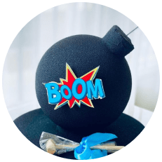 A black cake adorned with a boom sign, resembling a bomb cake.